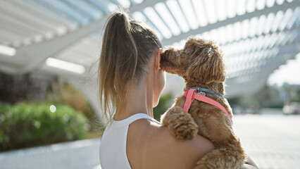 Young caucasian woman with dog kissing ear at park
