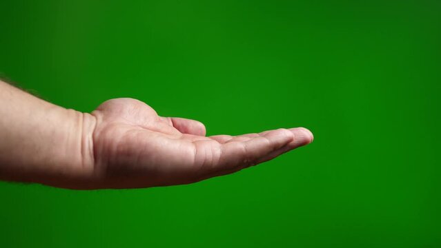 A man puts his palm with a request for something on a green background.