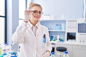Young blonde woman scientist smiling confident standing at laboratory