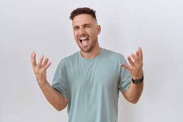 Fototapeta premium Hispanic man with beard standing over white background celebrating mad and crazy for success with arms raised and closed eyes screaming excited. winner concept