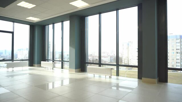 View of an empty spacious hall with columns and panoramic windows. Modern interior design of an empty office. A room with large windows, doors and an elevator.