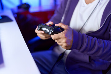 Young hispanic man streamer playing video game using joystick at gaming room