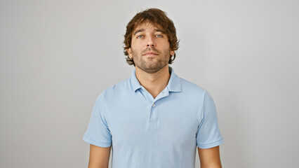 A handsome caucasian man with a beard in a blue shirt stands against a white isolated background,...