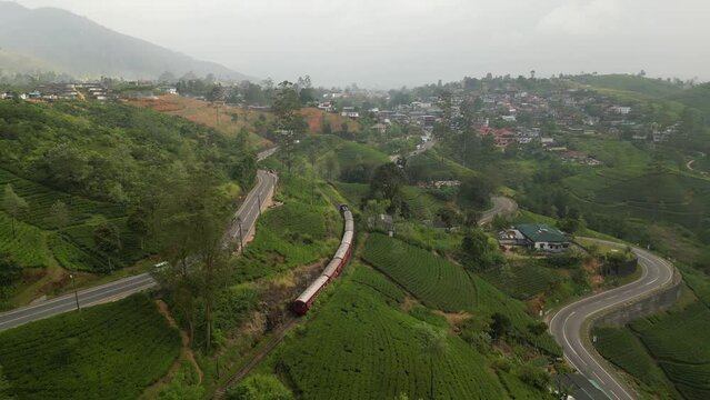 A passenger train passes the green hills with tea plantations in Hatton town, Sri Lanka