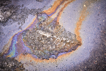 Background of a puddle of gasoline spilled on the road. Gasoline leak. A colorful stain of engine oil on the road.