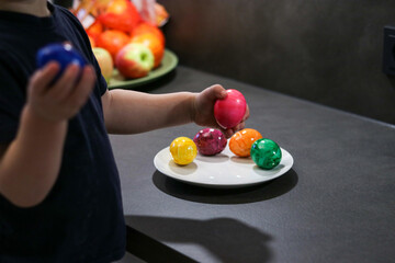 Little toddler boy holding colorful easter eggs, blurry background