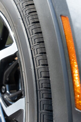 Front fender of a modern car with tire in focus and reflector out of focus in the foreground