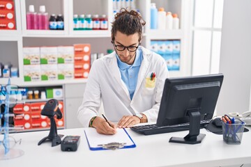 Young hispanic man pharmacist writing on document at pharmacy