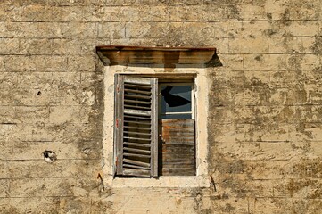 Fototapeta na wymiar Broken window blocked with boards in an old abandoned house
