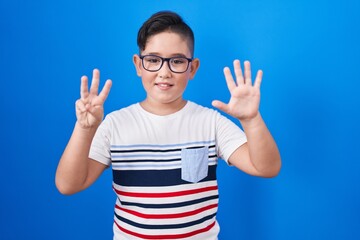 Young hispanic kid standing over blue background showing and pointing up with fingers number eight while smiling confident and happy.