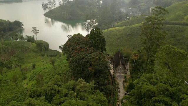 A colonial Christian Church on the hill by the lake among the patterned tea plantations. Highland nature landscape of Sri Lanka