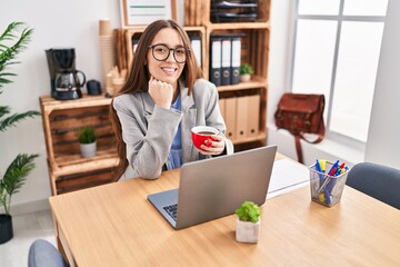 Young beautiful hispanic woman business worker using laptop drinking coffee at office