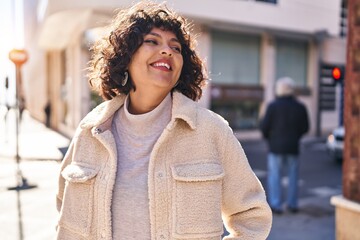 Young beautiful hispanic woman smiling confident looking to the side at street