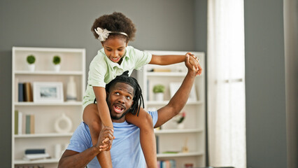 African american father and daughter smiling confident dancing with child on shoulders at home
