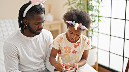 African american father and daughter wearing funny diadem playing with makeup at bedroom