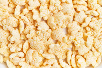 Close-up of numerous crisp rice cereal pieces scattered on a white background.