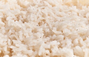 Close-up view of cooked white rice grains seasoned with specks of black pepper, hinting at a simple, staple food.
