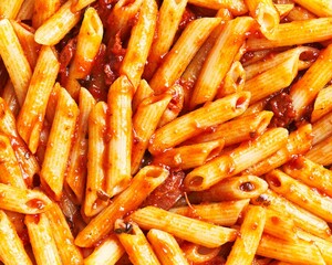 Close-up of delicious penne pasta coated in rich tomato sauce focusing on italian cuisine.