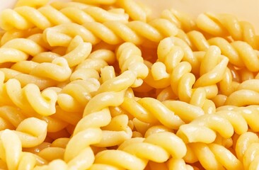 Close-up of cooked fusilli pasta glistening with moisture, ready for culinary use or recipe...