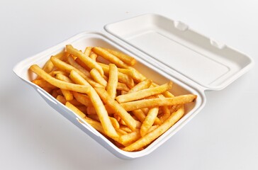 Close-up of golden french fries in a white styrofoam container set against a clean background.