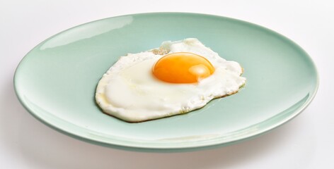 A sunny-side-up egg served on a pastel green plate isolated on a white background, depicting a simple and healthy breakfast.