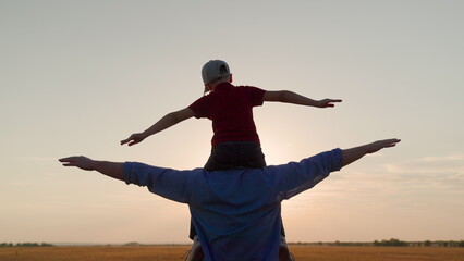 Father Son play together in front of sun, dream, fly. Dad, child fantasize, kid aviator sits on his...