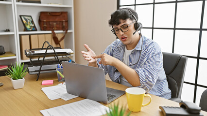 A professional man explains a point during a video call in a modern office setting, showcasing technology and communication.