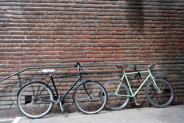 Bicycle locked and parked at empty brick wall building railing background. Copy space, ad template