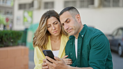 Man and woman couple using smartphone worried at street