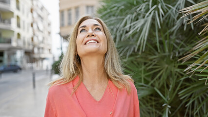 Fototapeta premium Smiling mature woman in casual wear enjoying a sunny day in an urban environment.