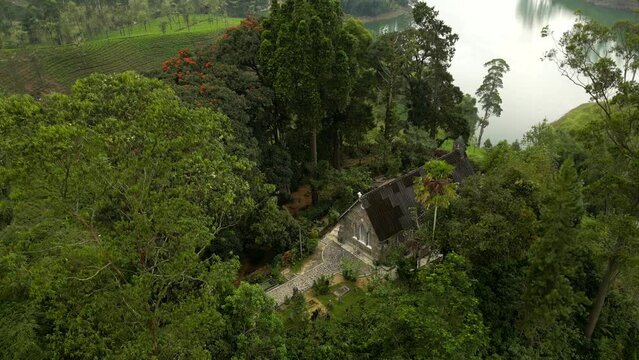 A colonial Christian Church on the hill by the lake among the patterned tea plantations. Highland nature landscape of Sri Lanka