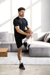 Handsome man with athletic body doing squats at home