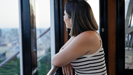 Young beautiful hispanic woman riding in big wheel looking at the views at Prater Vienna