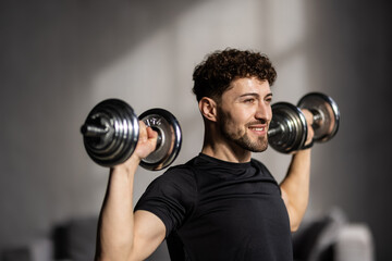 Closeup of handsome man doing dumbbell workout at home, working on arms strength.