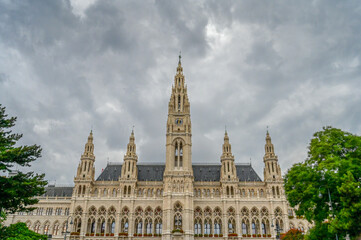 Fototapeta premium Vienna, Austria: The Vienna City Hall building on Rathausplatz with dramatic dark clouds in background. Office of the Mayor of Wien, seat of city council and local government.