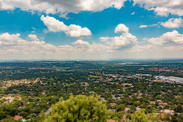 Clear Elevated Panoramic view of Johannesburg - Western View from Northcliff with trees in foreground and white clouds in a blue sky