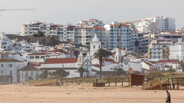 Aerial view of beautiful Meia Praia beach timelapse in Lagos, Algarve, Portugal at morning. Many houses on cliffs. Close up view with church and crane