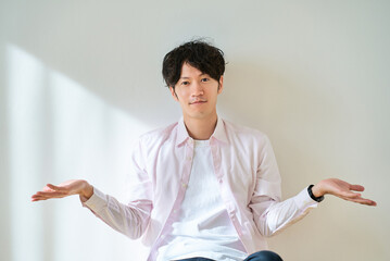 2つの選択肢を比較するようなポーズをする若い男性