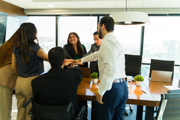 Naklejka premium Diverse team of businesspeople putting their hands together in a meeting room
