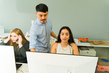 Male supervisor helping a woman with some technical issues in the office