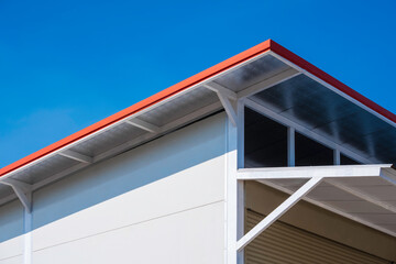 Storage room is made from white fiber cement board wall with steel shed roof and heat insulation against blue sky background, low angle and perspective side view