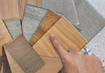 architect's hand selects collection of wooden interior material samples swatch contains vinyl...
