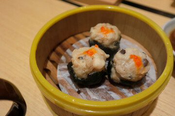 Chicken dimsum served in bamboo plate. Dimsum is a large range of small dishes that Cantonese people traditionally enjoy in restaurants for breakfast and lunch.