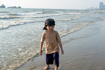 Little Asian boy playing in the sand at the sea beach