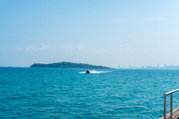 Seascape with speed boats coming to the pier, back view of Pattaya city, Thailand