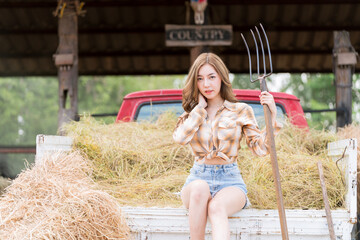 Cheerful pretty young woman cowgirl with truck. Beautiful cowboy style model posing on farmland.