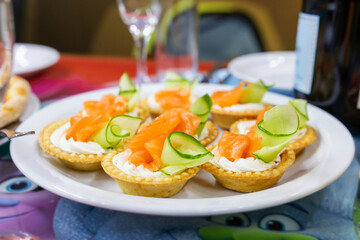 Tartlets with cream cheese, smoked salmon, and cucumber on a festive plate