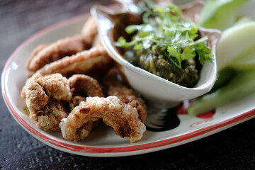 Pork rind, Pork scratchings, Pork crackling with Nam Prik Num or northern Thaig Green chilli dip on white plate and herbal vegetables. Thailand food