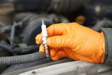 Close up mechanic hand hold old spark plug, spare part of car engine. Concept, machine maintenance,...