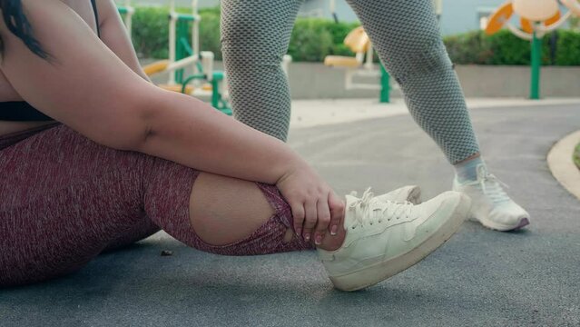 Closeup leg of plus size woman accident and sprain ankle while friends help and first aid at park, accident and hurt with foot during workout of fat woman, activity and emergency.
